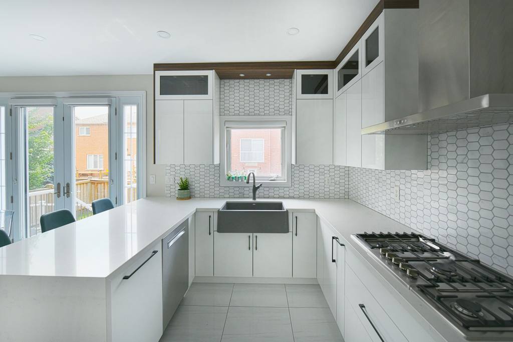 Bright white kitchen with a large island, farmhouse sink and shaker-style cabinetry